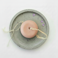 Shampoo solido nutriente su vassoio in cemento con petali di fiori viola e rafia naturale